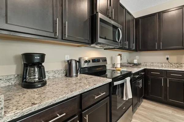 a kitchen with granite countertop a sink a stove and cabinets