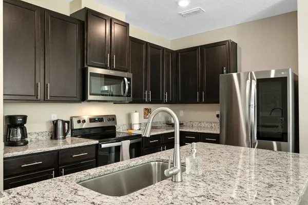 a kitchen with granite countertop a refrigerator stove and sink