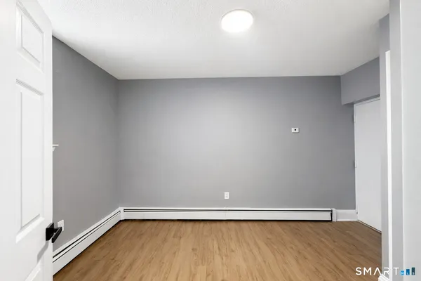 a view of an empty room with wooden floor and closet area