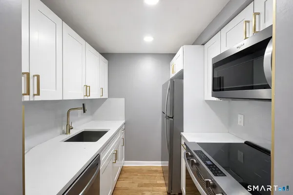 a kitchen with stainless steel appliances a sink a stove and cabinets