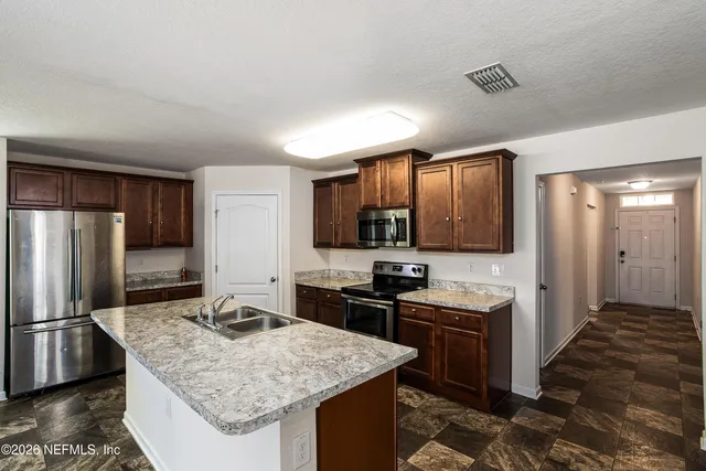 a kitchen with stainless steel appliances granite countertop a sink stove and refrigerator