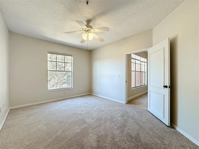 an empty room with windows and chandelier fan