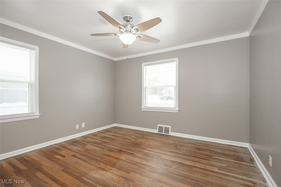 12328 Granger Road Cleveland, OH 44125 - Photo 10 of 37 Unfurnished room featuring crown molding, dark wood-type flooring, and ceiling fan
