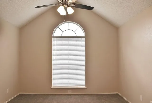 an empty room with windows and chandelier fan