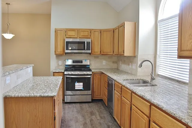 a kitchen with stainless steel appliances granite countertop a stove a sink and a microwave