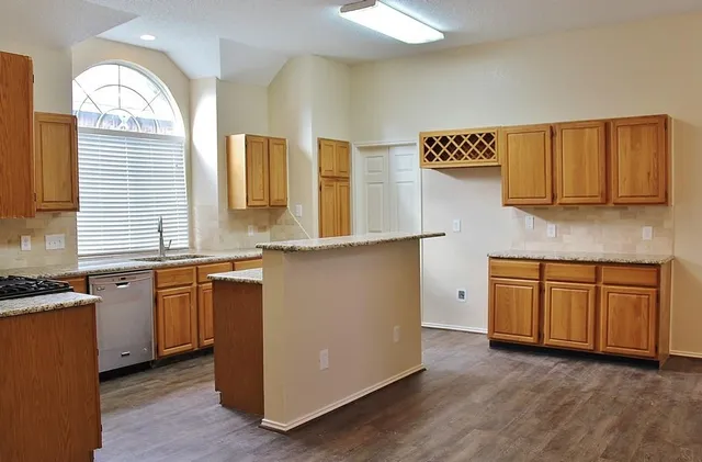 a kitchen with stainless steel appliances granite countertop a sink a stove and a wooden floors