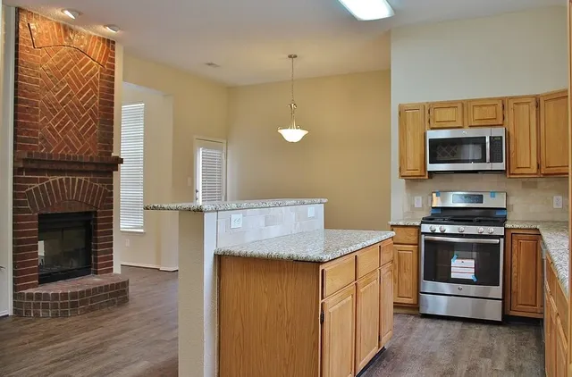 a kitchen with stainless steel appliances granite countertop a stove a sink and a microwave