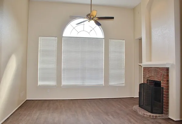 an empty room with windows and fireplace