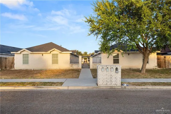 a view of a white house with a road and a large tree