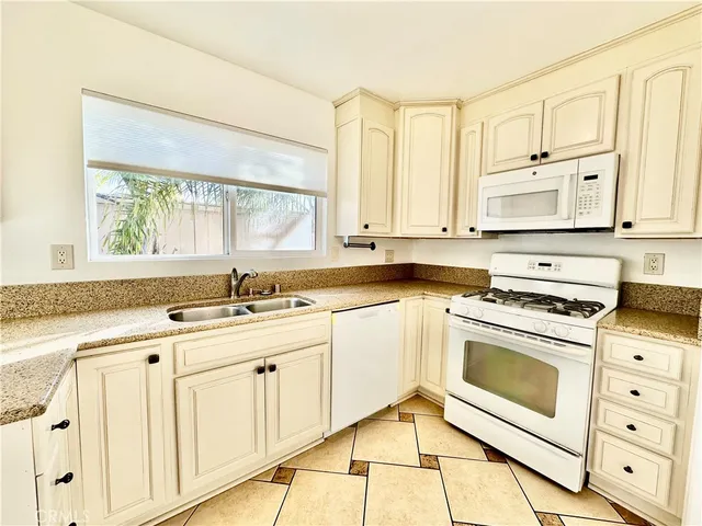 a kitchen with granite countertop white cabinets and white appliances