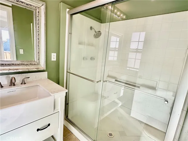 a bathroom with a sink a glass door shower and a mirror