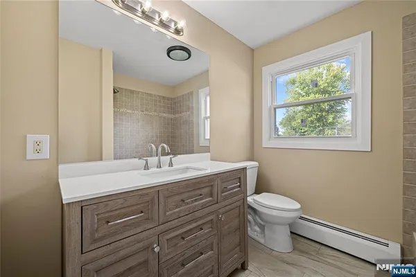 a bathroom with a toilet a sink a mirror and a window