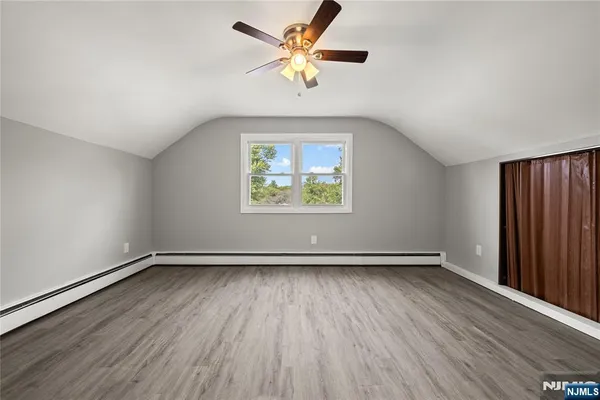 an empty room with wooden floor chandelier fan and windows