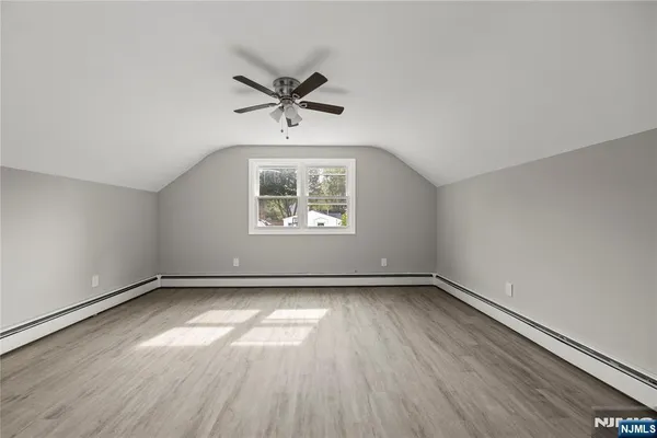 an empty room with wooden floor fan and windows