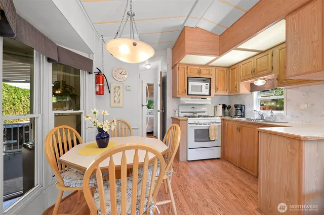 a kitchen with stainless steel appliances granite countertop a stove a sink dishwasher and white cabinets with wooden floor