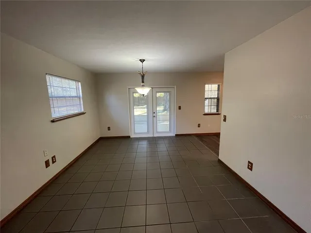 an empty room with wooden floor fireplace and windows