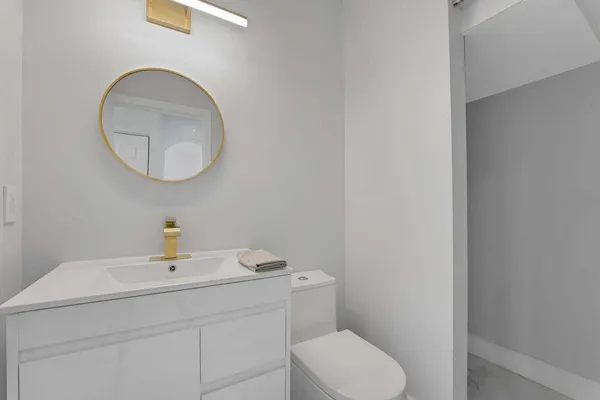 a bathroom with a toilet sink vanity and mirror