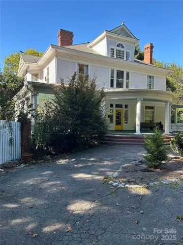 a view of a white house next to a road and yard