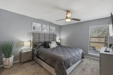 a bedroom with a large bed and a chandelier fan