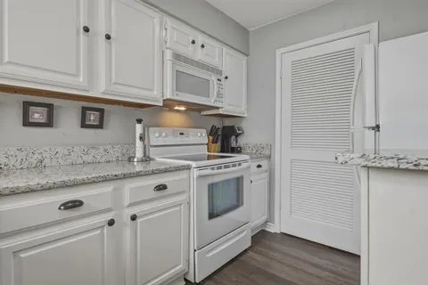 a kitchen with granite countertop white cabinets and white appliances