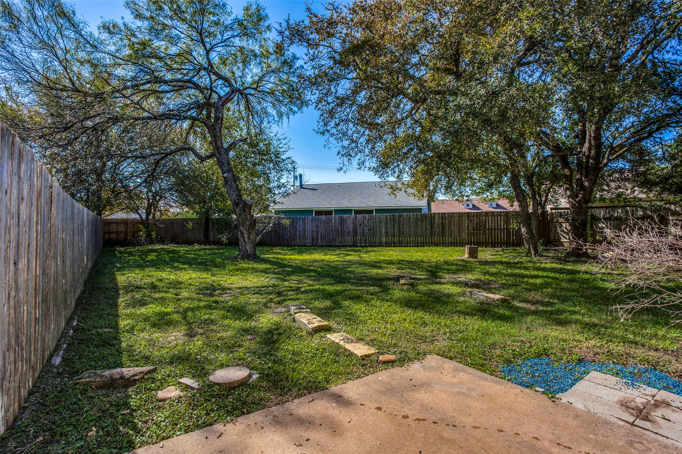 106 Verna Spur, Unit B Georgetown, TX 78628 - Photo 23 of 25 A spacious backyard awaits, complete with mature trees and a sturdy wood fence for privacy.