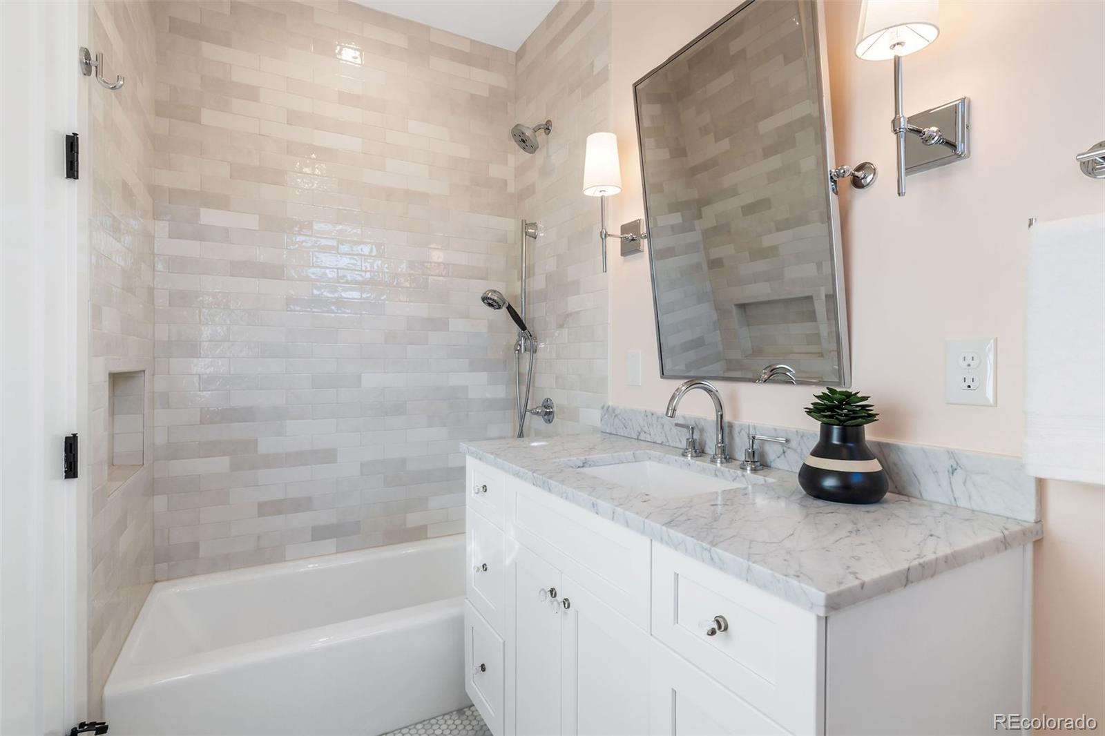 1026 South High Street Denver, CO 80209 - Photo 36 of 50 a bathroom with a granite countertop sink a large mirror and a bathtub