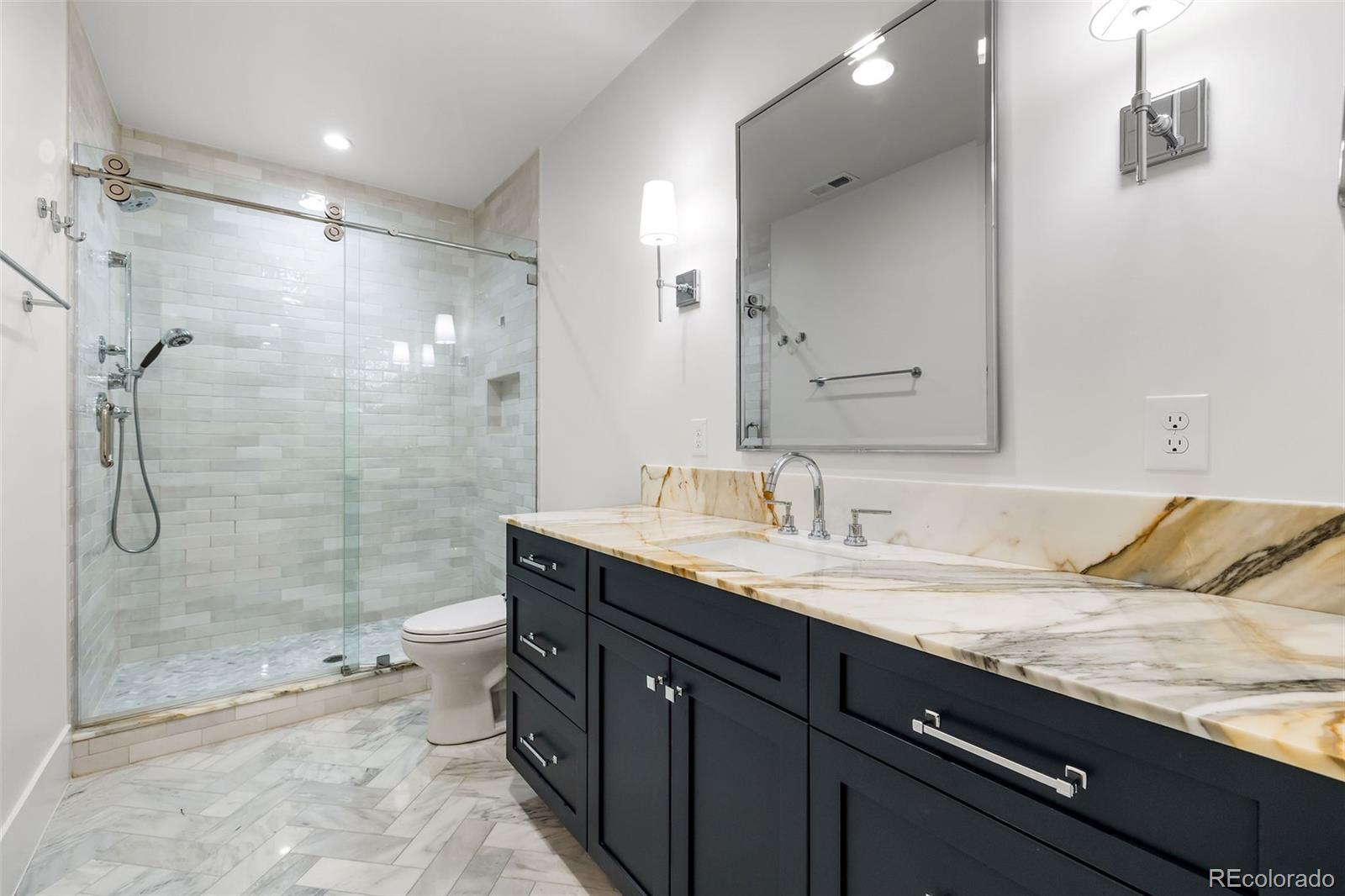 1026 South High Street Denver, CO 80209 - Photo 43 of 50 a bathroom with a granite countertop sink a toilet a mirror and shower