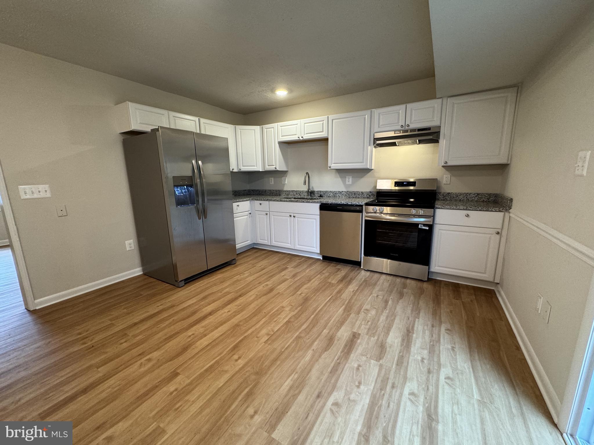 5140 Redbud Road Fredericksburg, VA 22407 - Photo 7 of 22 a kitchen with stainless steel appliances wooden floors and wooden cabinets