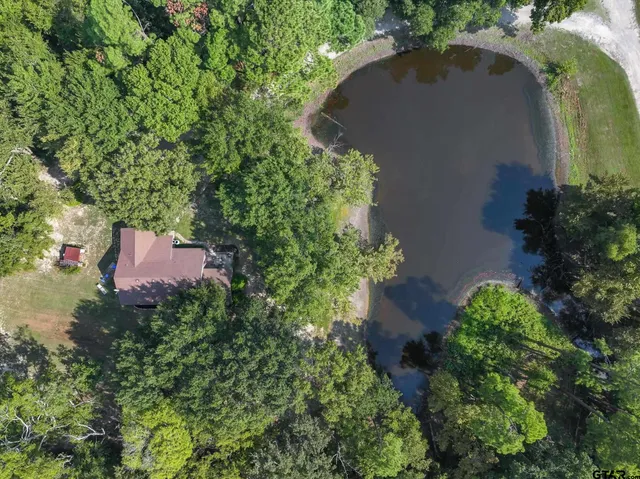 an aerial view of a house with a yard and trees all around