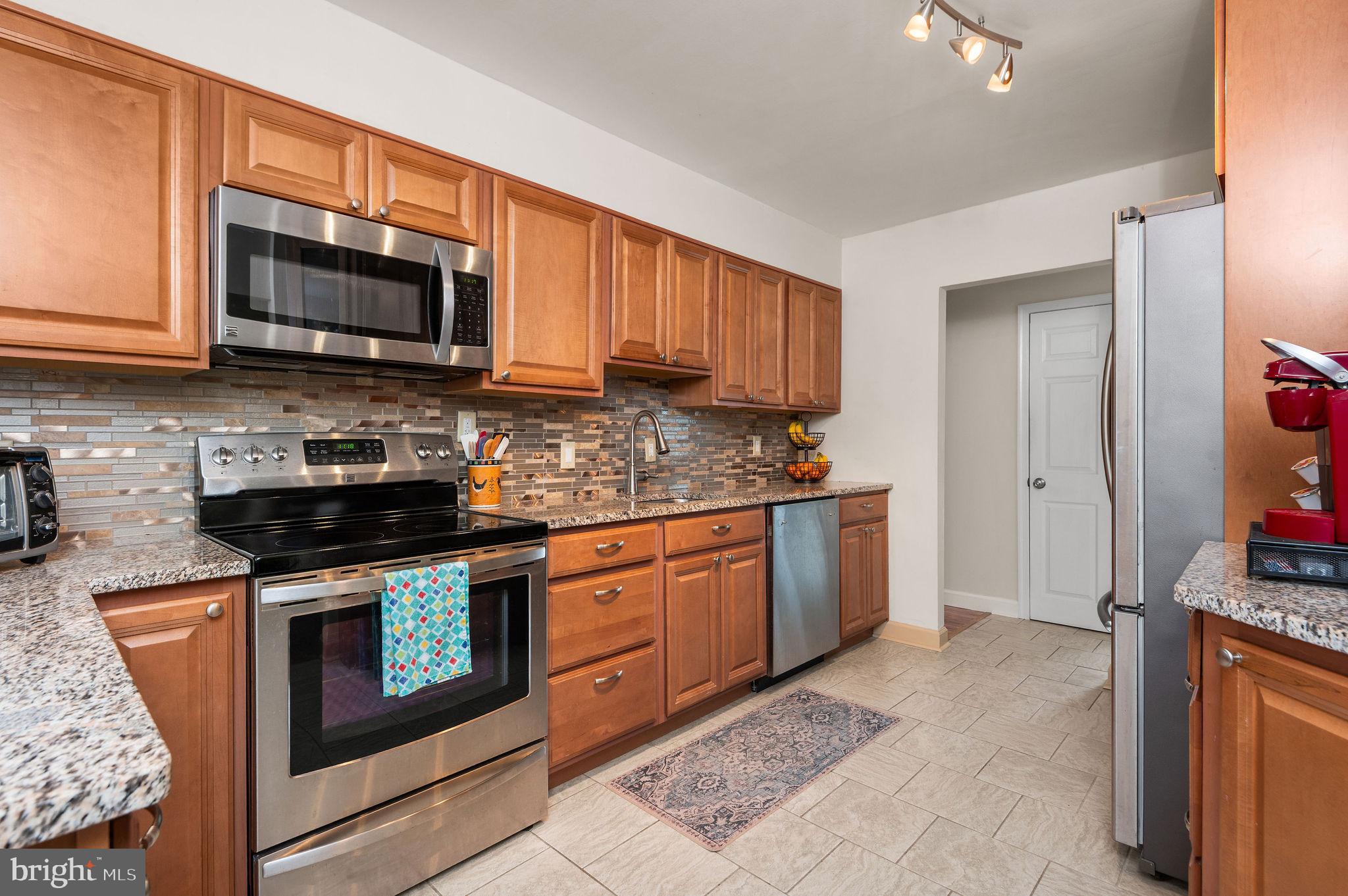 a kitchen with stainless steel appliances granite countertop a stove top oven microwave and cabinets