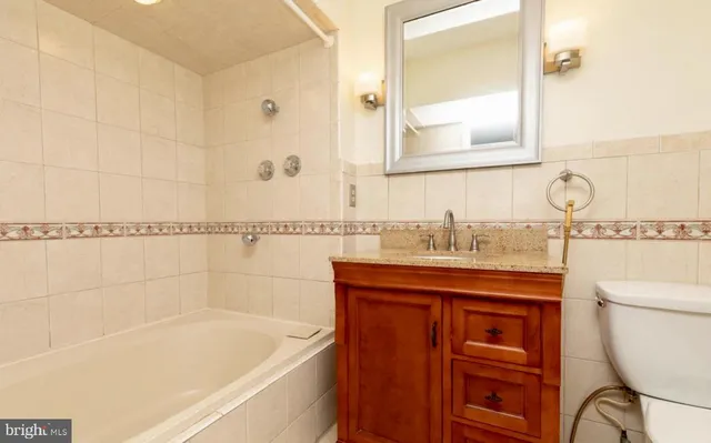 a bathroom with a granite countertop sink a mirror and a bathtub