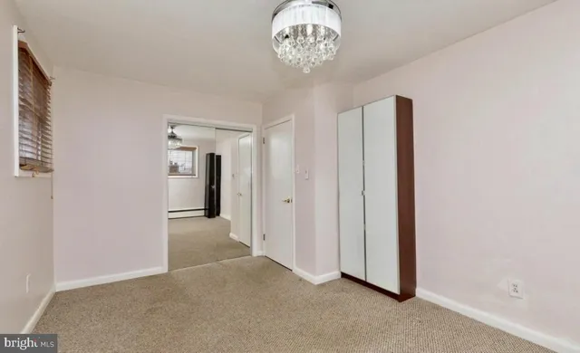 an empty room with a chandelier fan and wooden floor