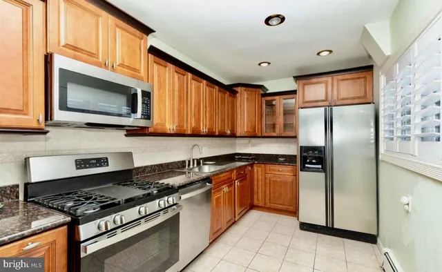 a kitchen with stainless steel appliances granite countertop a stove top oven a refrigerator and a sink