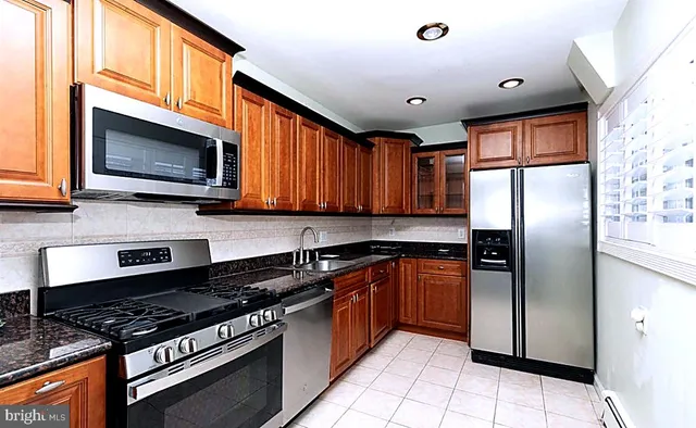 a kitchen with stainless steel appliances granite countertop a stove top oven a refrigerator and a microwave