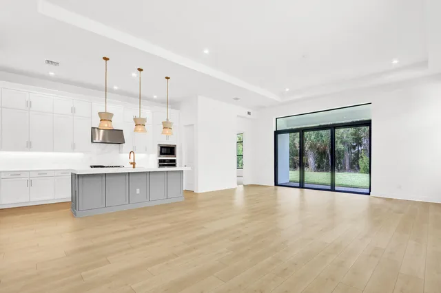 a large kitchen with stainless steel appliances granite countertop a stove a sink and a large window with wooden floor