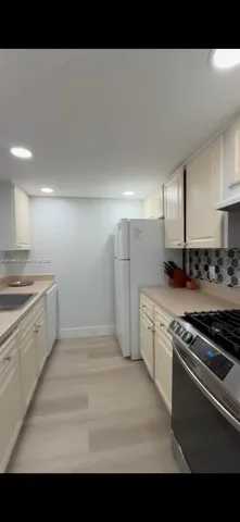 a kitchen with granite countertop a sink stove and refrigerator