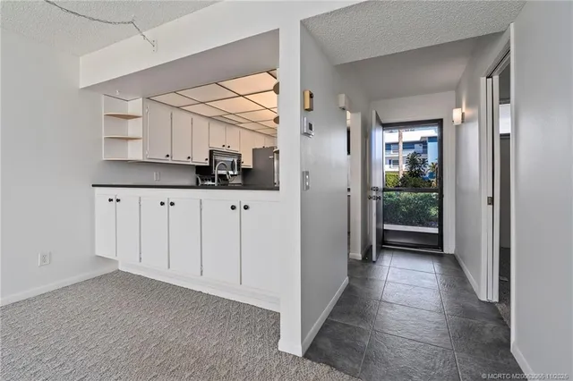 a view of a hallway to room with wooden floor and cabinet