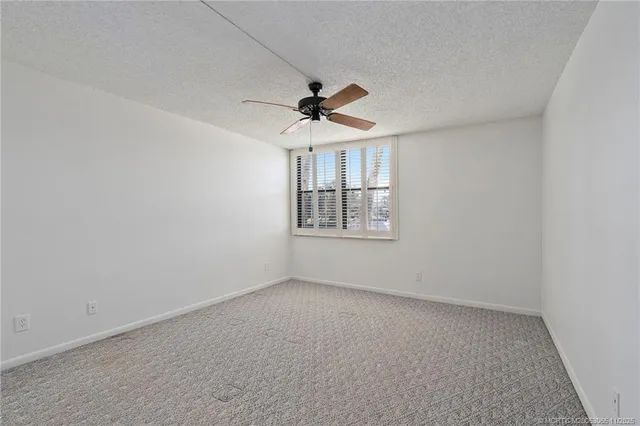 an empty room with a ceiling fan and windows