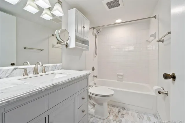 a bathroom with a granite countertop sink a toilet and shower