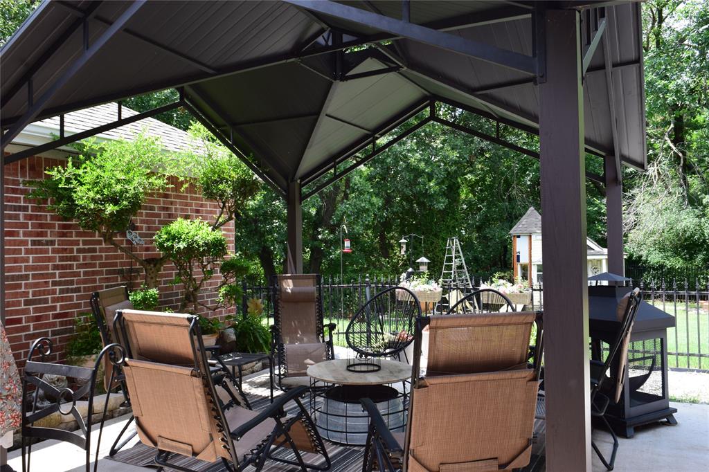 4201 Glistening Spring Rowlett, TX 75088 - Photo 26 of 33 Covered patio space featuring a dark-toned gazebo with a pitched roof, brick exterior wall, and landscaped plantings