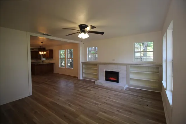 an empty room with wooden floor fireplace and windows