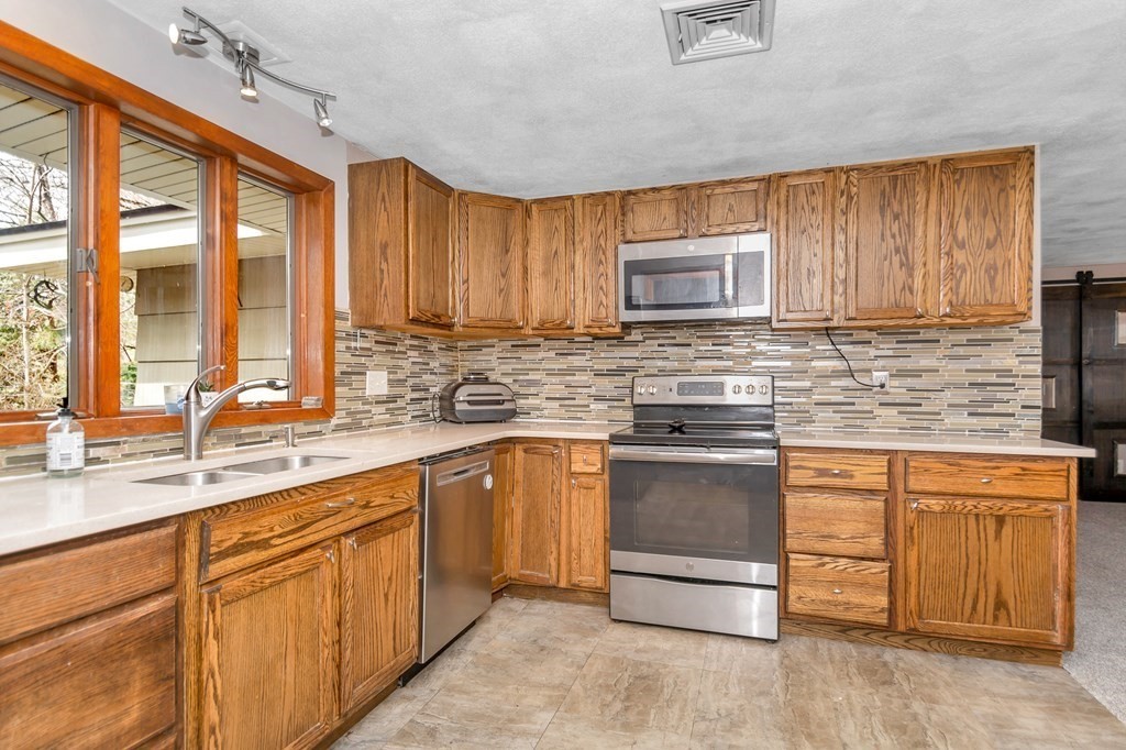 13 Ranch Road Chelmsford, MA 01824 - Photo 6 of 42 a kitchen with stainless steel appliances granite countertop a stove a sink and a microwave