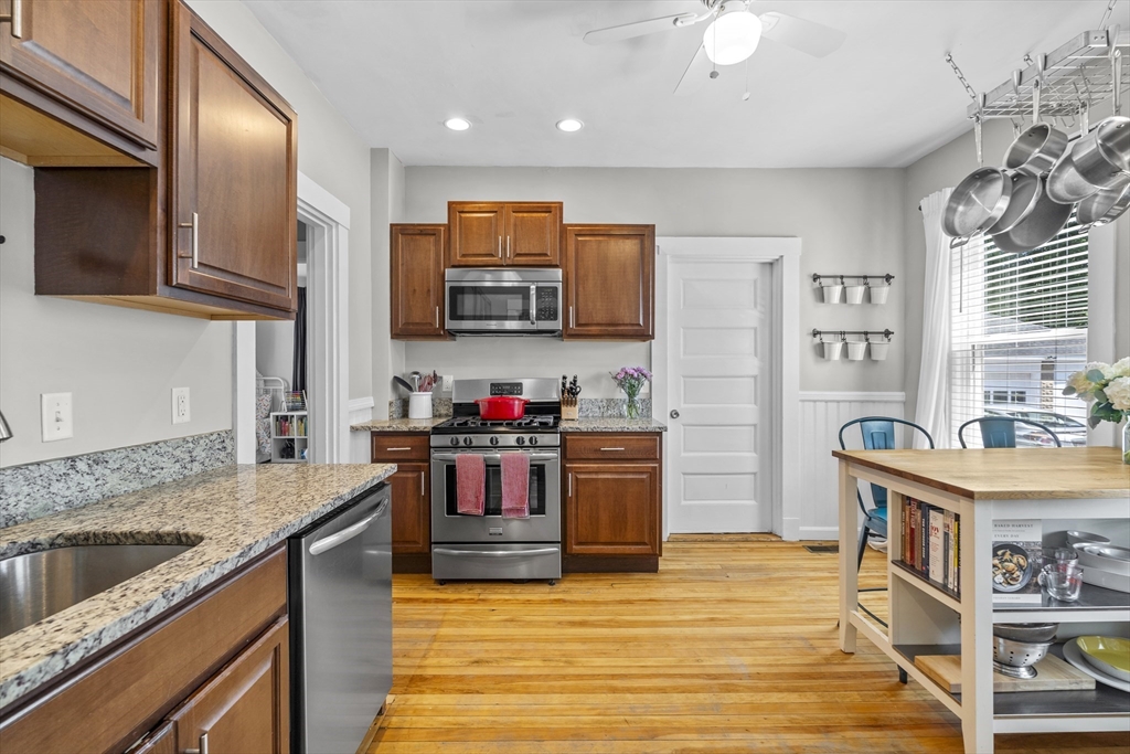 30 Chester Avenue, Unit 1 Waltham, MA 02453 - Photo 4 of 14 a kitchen with stainless steel appliances granite countertop a sink dishwasher stove and refrigerator with wooden floor