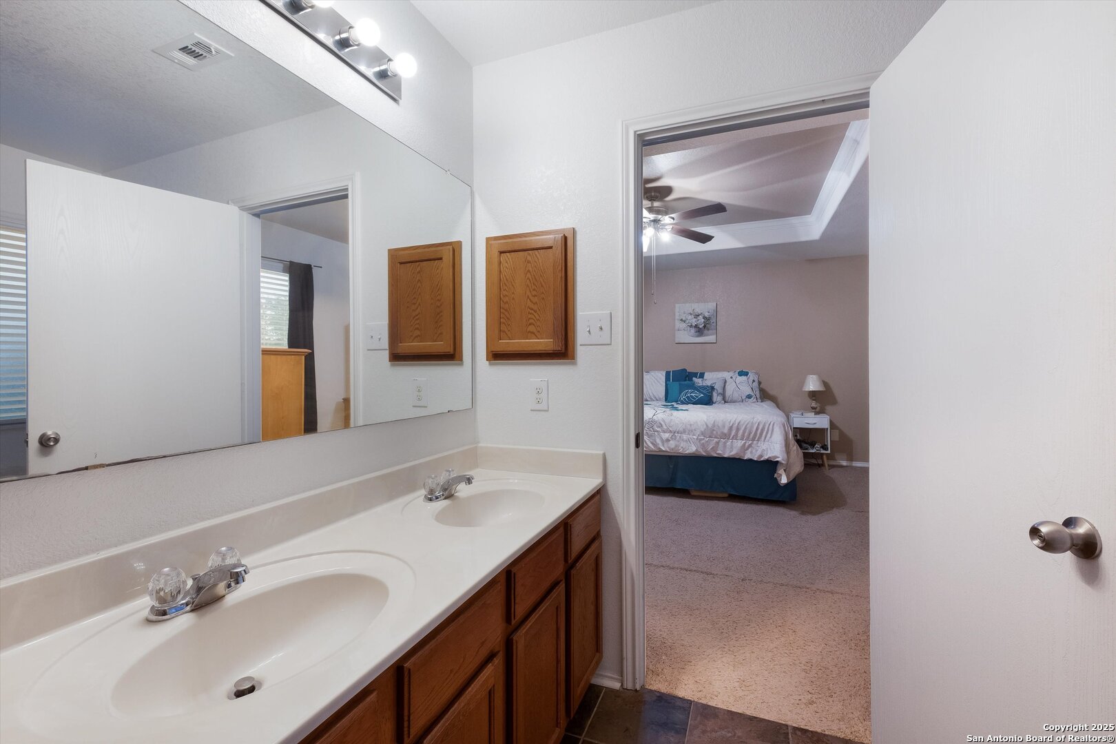 10711 Rindle Ranch San Antonio, TX 78249 - Photo 19 of 31 a en suite bathroom with a double vanity sink and mirror