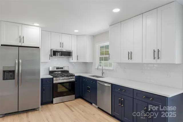 a kitchen with stainless steel appliances granite countertop a sink a stove a refrigerator and cabinets