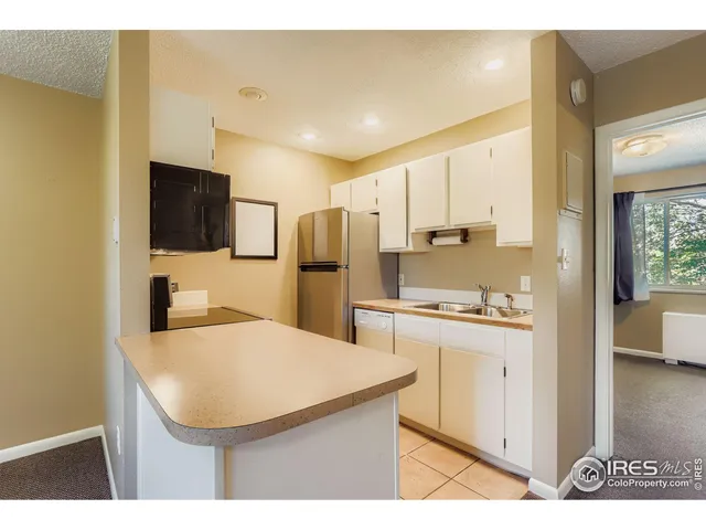 a kitchen with stainless steel appliances kitchen island granite countertop a refrigerator a sink a stove with white cabinets