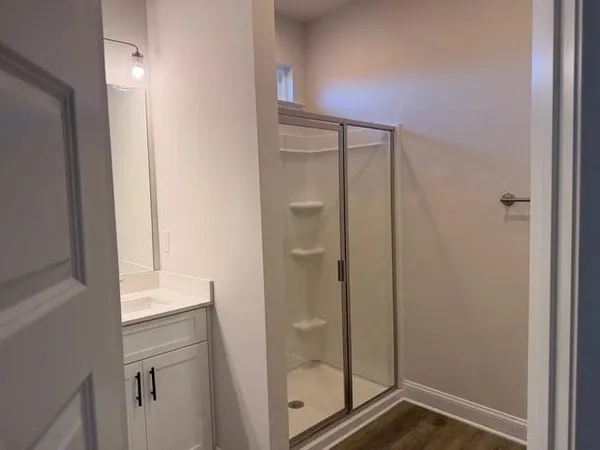 a bathroom with a granite countertop sink two mirror and shower