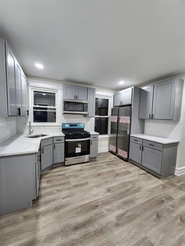 a large kitchen with cabinets wooden floor and stainless steel appliances