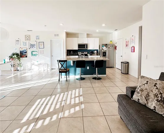 a living room with couches and kitchen view with wooden floor