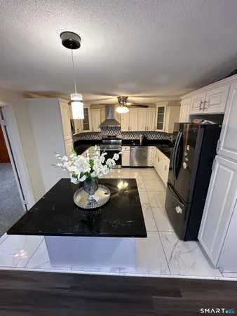 a large kitchen with stainless steel appliances granite countertop a refrigerator and a stove